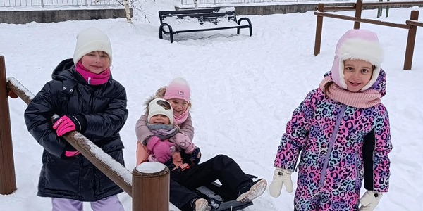 Dzieci z sankami bawiące się na śniegu