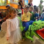 Tańczący aniołek obok chłopca w przebraniu tyranozaura